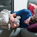 Person lying on a couch holding a weighted comfort elephant .
