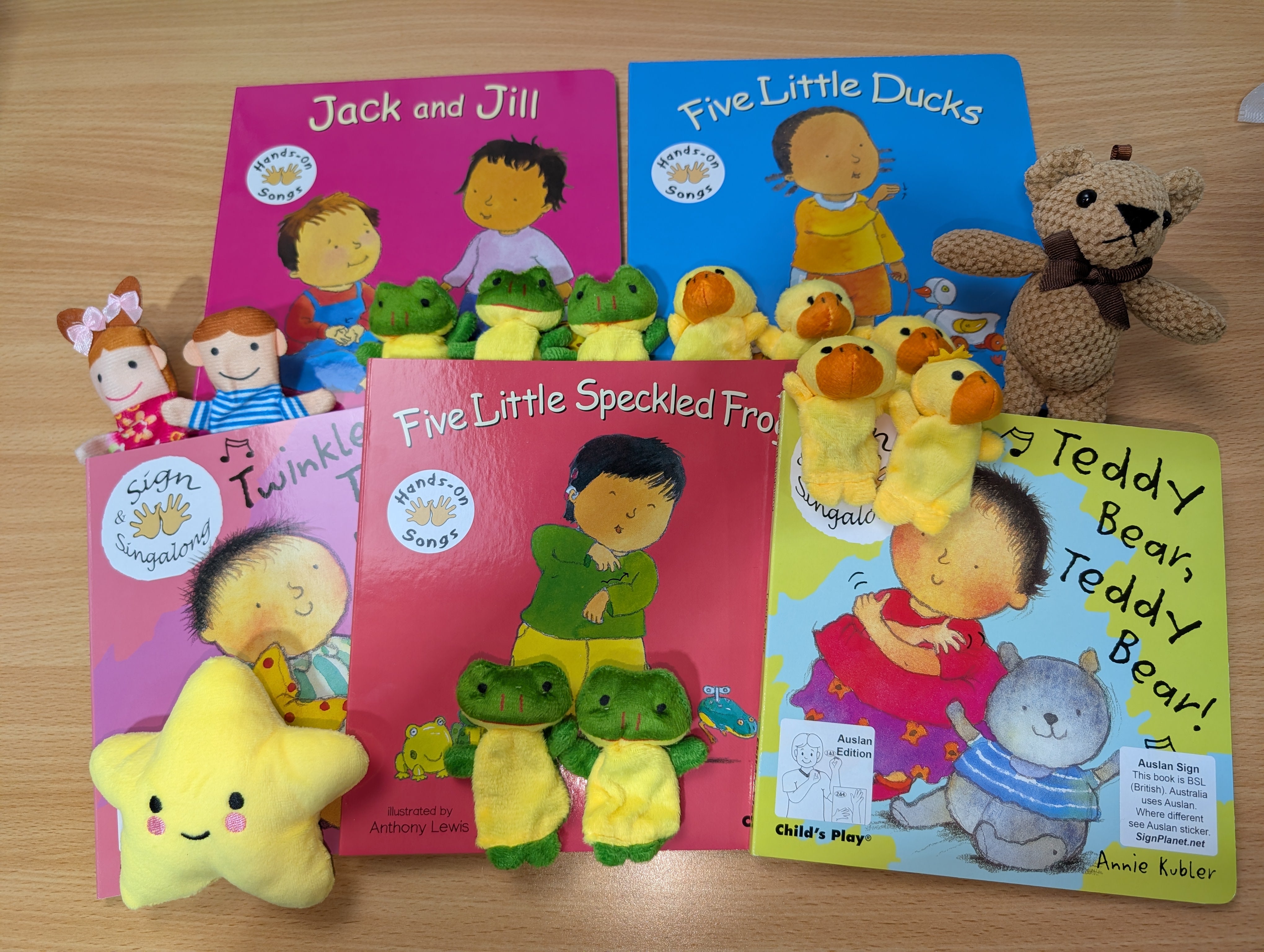 Set of children's books with corresponding plush toys on a wooden surface